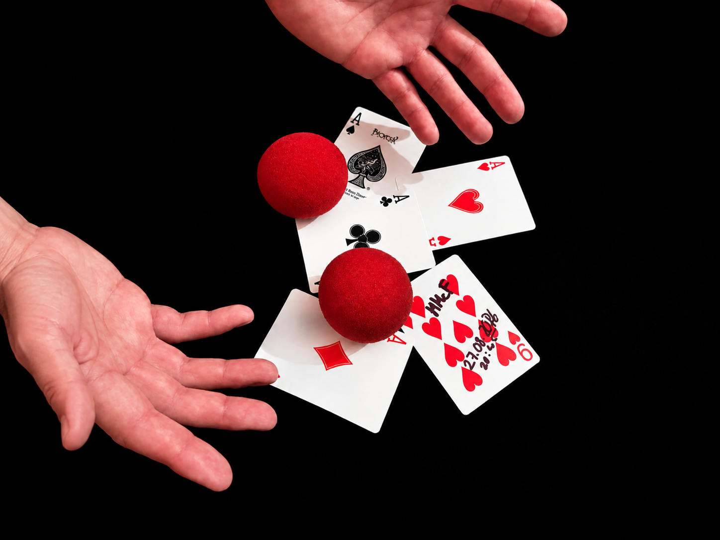 Hände mit Spielkarten und roten Schwammbällen auf schwarzem Hintergrund