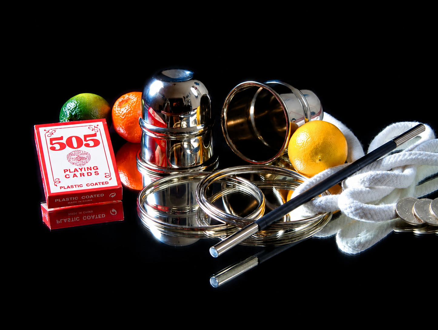 Zauberrequisiten: Becher, Ringe, Seile, Spielkarten und Früchte auf schwarzem Hintergrund