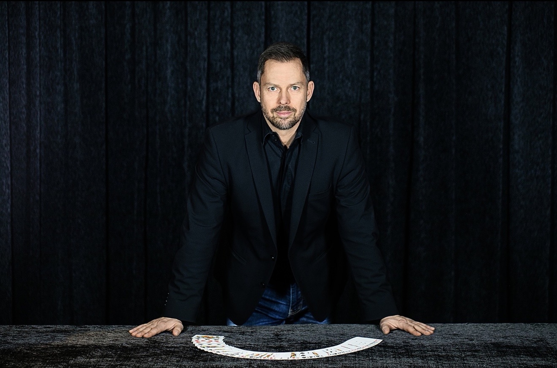 Jörg Borrmann am Tisch mit aufgefächerten Spielkarten